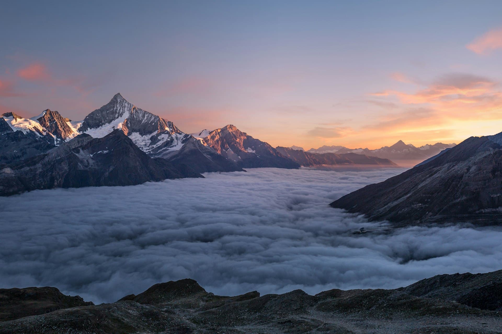 Mountain peaks above clouds at sunset